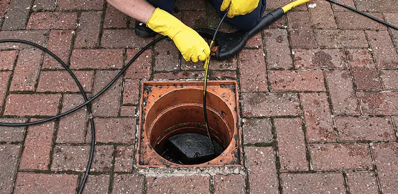 Drain cleaning technician using a drain snake to clear a clogged drain in Houston, TX
