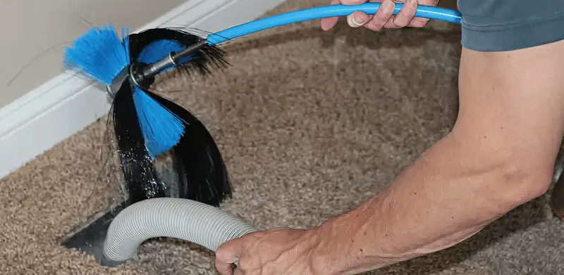 Dryer vent cleaning technician brushing lint from a vent line in Houston, TX