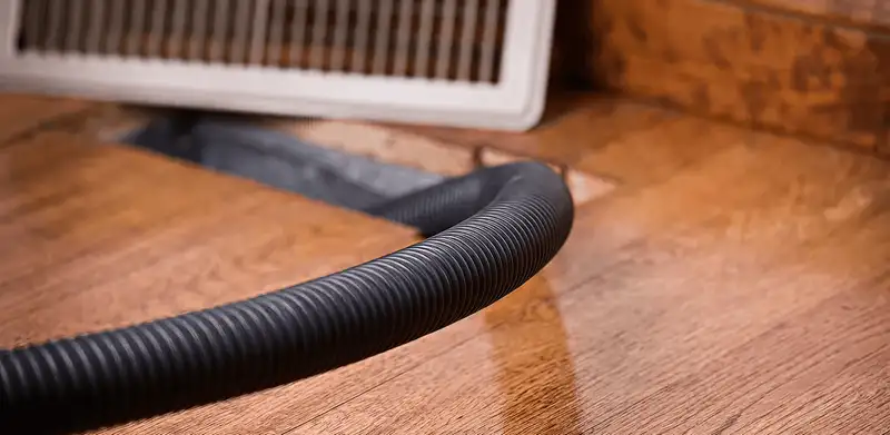 Air duct cleaning hose inserted into a floor vent for ductwork cleaning in Houston, TX